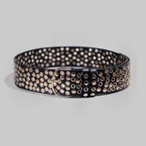 Cinturón negro de cuero sintético con hebilla dorada y apliques de tachas doradas de diferentes tamaños.