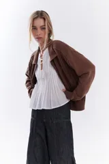 Blusa blanca sin mangas de algodón, con diseño de tablas frontales y escote con lazos para atar.