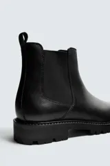 Bota tipo Chelsea fabricada en piel, con diseño de parte superior lisa, piezas elásticas laterales y tirador trasero. Presenta horma redonda y suela con volumen y piso track.