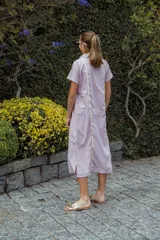 Vestido camisero midi color lila con cuello camisero, cierre frontal con botones y aberturas laterales.