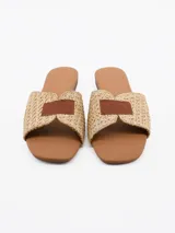 Sandalias bajas color beige con capellada tejida y detalle de etiqueta de cuero marrón.