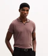 Camisa polo de manga corta color malva, confeccionada en algodón con cuello en V y detalles de ribete en color negro en el cuello y los bordes de las mangas.