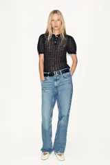 Polo negro de punto calado con cuello clásico, manga corta abullonada y terminación ondulada en el ruedo.