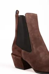 Bota tipo Chelsea de gamuza color marrón, con paneles laterales elásticos en color negro, puntera cuadrada y taco cuadrado de altura media.