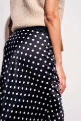 Falda midi de poliéster color negro con estampado de lunares blancos.
