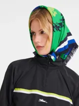 Pañuelo cuadrado de seda Longchamp, con estampado de caballos y jinetes en verde y azul.