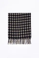 Bufanda rectangular con estampado pied de poule en tonos negro y beige, con terminación de flecos en los extremos.