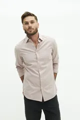 Camisa de manga larga lisa con cuello clásico, cierre frontal con botones y logo bordado en el pecho. Presenta un corte regular y un diseño atemporal.