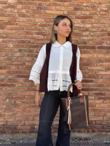 Bolso matero de cuero color chocolate con textura croco, asas cortas y detalle de costuras en los laterales. Incluye un dije con flecos en tonos beige y negro.