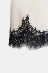 Shorts de tiro alto confeccionados en tejido satinado color crema, con cintura elástica y detalle de encaje negro a contraste en el bajo.