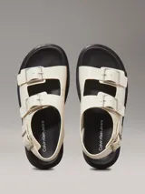 Sandalias de piel lisa color blanco con suela de goma negra, tiras anchas con hebillas metálicas ajustables y plantilla moldeada.