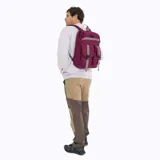 Mochila urbana Merrell de color bordó, confeccionada en poliéster canvas. Cuenta con un compartimento principal con cierre, un bolsillo frontal con dos correas ajustables con hebillas y una cinta horizontal decorativa. Incluye logo de la marca en la parte superior.