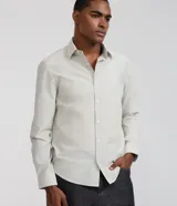Camisa de sastrería para hombre, de corte regular, color blanco con finas rayas verticales grises. Cuenta con cuello solapa, cierre frontal con botones y mangas largas.