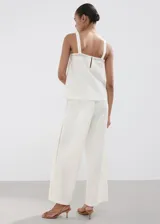 Pantalón palazzo color blanco con detalles bordados en el bajo de las piernas, tiro medio y cintura elástica con cordón ajustable.