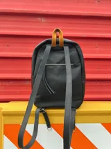 Mochila de cuero sintético color marrón y beige con textura símil cocodrilo, cierre superior con doble cremallera y tiradores de cuero, bolsillo vertical frontal con cremallera, bolsillo trasero oculto con cremallera, interior forrado con bolsillo con cremallera y correas regulables.