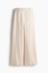 Pantalón sastrero de tiro alto en mezcla de lino y viscosa, de corte amplio y perneras rectas con pliegues frontales. Cuenta con trabillas para cinturón, cierre frontal con cremallera y corchete, y bolsillos laterales discretos.