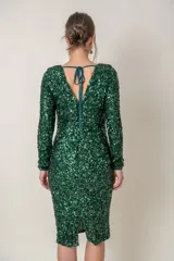 Vestido corto verde esmeralda de paillettes con escote en V y mangas largas. Presenta detalle de strass en el escote y la cintura, y corte recto.