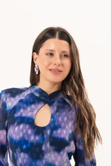Vestido largo de manga larga con terminación campana, de color azul y violeta con estampado tie-dye, cuello mao con ojal y tajo frontal. Cuenta con flecos en el ruedo y tajo en la pierna.