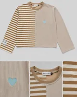 Buzo oversize de corte asimétrico con diseño combinado de rayas verticales y horizontales en tonos beige y blanco. Presenta un corazón bordado en color celeste en el frente y una etiqueta decorativa en la manga.
