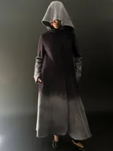 Tapado largo de lana merino color gris oscuro con teñido degradado en gris claro en ruedo, mangas y capucha. Tiene corte recto, bolsillos laterales y cierre cruzado con broches a presión ocultos en los hombros.