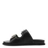 Sandalias tipo slide de color negro, con doble tira ajustable mediante hebillas metálicas doradas. Presentan un diseño decorado con pequeñas tachas metálicas a lo largo de las tiras y el contorno de la base.