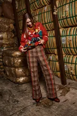 Sweater tejido a mano con lana color ladrillo, cuello redondo, puños y ruedo acanalados con rayas blancas. Presenta bordados con figuras de personas y animales.