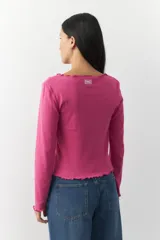 Remera blanca de manga larga con cuello redondo y costuras a la vista.