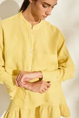 Camisa de lino italiano color beige, de corte holgado, con cuello mao, manga larga y bolsillo aplicado en el pecho.