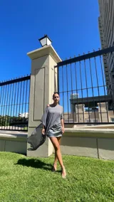 Vestido corto de satén con frunces laterales y acabado brillante, que incluye una capa desmontable de gasa transparente que se puede colocar de diversas formas.