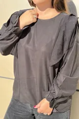 Blusa de algodón color bordó, con diseño de volados en los hombros, mangas largas con puños elásticos y corte holgado.