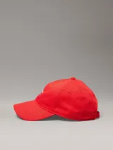 Gorra de béisbol roja con visera curva, confeccionada en algodón. Presenta el logo de Calvin Klein Jeans bordado en el frente en color azul.