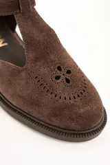 Sandalias cerradas de cuero marrón, con diseño tipo Mary Jane con tira en T, detalles perforados en la puntera y suela plana con pequeño tacón.