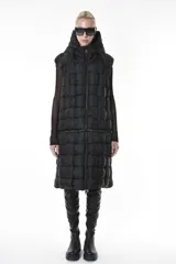 Chaleco puffer negro con diseño de cuadros, capucha y bolsillos laterales. Tiene cierre central y un cierre horizontal a la altura de la cadera que permite quitar la parte inferior, modificando el largo del chaleco.