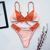 Bikini de dos piezas color naranja, con corpiño triangular con detalle de lazo frontal y bombacha cavada de tiro alto.