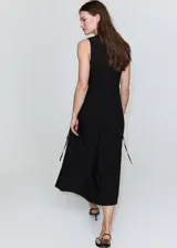 Vestido midi negro sin mangas, con cuello redondo y diseño recto con sutil frunce en los laterales de la cintura.