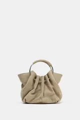 Bolso tipo saca de serraje color beige con doble asa rígida asimétrica y asa bandolera extraíble. Incluye cartera con bolsillo extraíble.