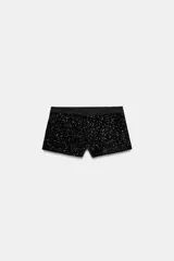 Short de tiro bajo de Zara Woman Collection, confeccionado con aplicación total de lentejuelas negras. Cuenta con pretina lisa, bolsillos delanteros y cierre frontal con cremallera y gancho metálico.