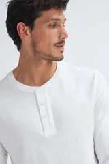 Remera manga larga de algodón en color blanco, con cuello redondo y tapeta frontal con tres botones.
