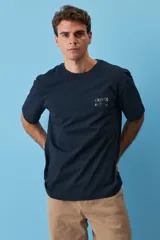 Remera blanca de algodón, de corte holgado y mangas cortas, con pequeño estampado azul en el pecho.