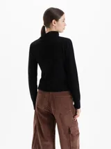 Sweater de lana merino color negro, con cuello medio alto y detalle de frunces en los hombros que aportan volumen. De calce regular y tejido suave.