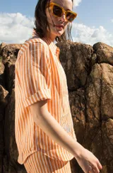 Camisa de manga corta oversize en lino rayado, con cuello camisero, cierre frontal con botones y bordado playero en el frente.