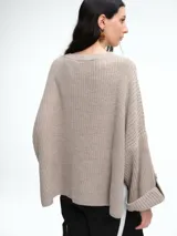 Sweater de tejido de punto color marrón con textura tipo waffle, diseño amplio, hombros caídos y cuello redondo. Presenta un bolsillo frontal aplicado y mangas con puños anchos decorados con botones.