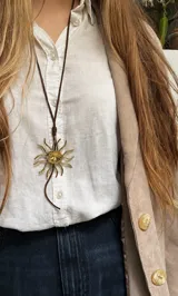 Set de accesorios compuesto por un collar, un brazalete y dos pares de aros, todos elaborados en bronce, presentados en un sobre de cuero marrón tipo gamuza.
