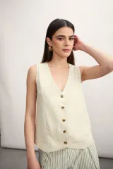 Chaleco sin mangas de corte recto y escote en V, con cierre frontal de botones en contraste. Presenta un diseño minimalista y estructurado.
