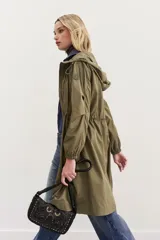 Campera impermeable color verde militar, de calce amplio y largo tipo parka. Posee capucha, bolsillos y puños elastizados, y cintura regulable con cordón.