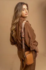 Bandolera compacta color rojo con textura de cuero, correa regulable y desmontable con diseño de rayas rojas y blancas. Cuenta con bolsillos frontales y cierre, interior forrado en tela.