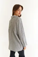 Camisa de corte oversize color bordó, con cuello clásico, cierre frontal de botones y detalle de trenzado horizontal en la parte superior delantera. Posee mangas largas con puños abotonados.