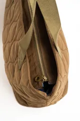 Bolso tipo tote bag color marrón con diseño capitonado de ondas, asas largas y placa metálica con el logo de la marca.
