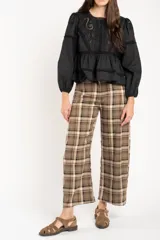 Pantalón de corte recto y tiro medio con estampado de cuadros escoceses en tonos marrones y beige. Presenta cierre frontal con botón y bolsillos laterales.