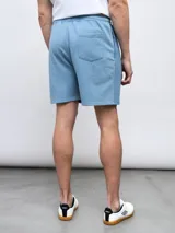 Bermuda de felpa negra con efecto lavado, corte recto y cordón ajustable en la cintura. Presenta un panel vertical en la parte delantera de cada pierna y el logo Umbro bordado en blanco en el muslo izquierdo.